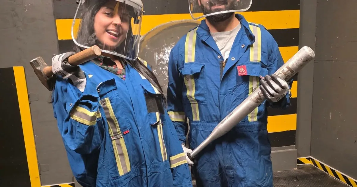 Two guests wearing protective gear and holding smash tools at Smash & Splatter