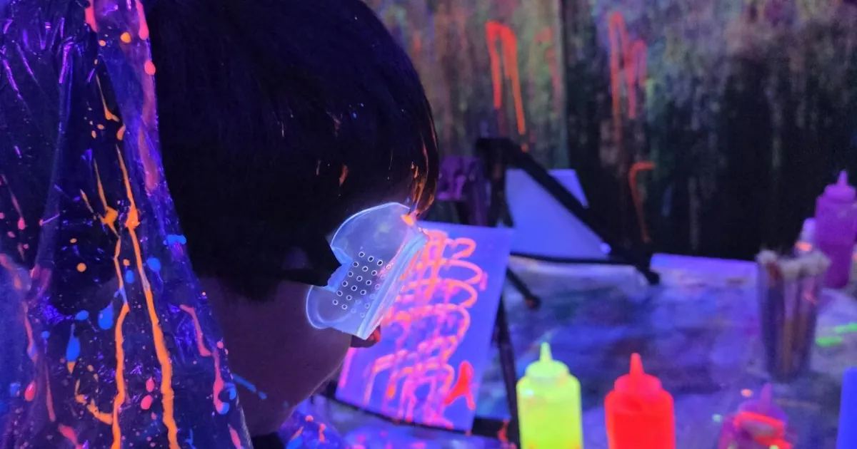 Person painting a canvas under blacklights at Smash & Splatter in Lloydminster