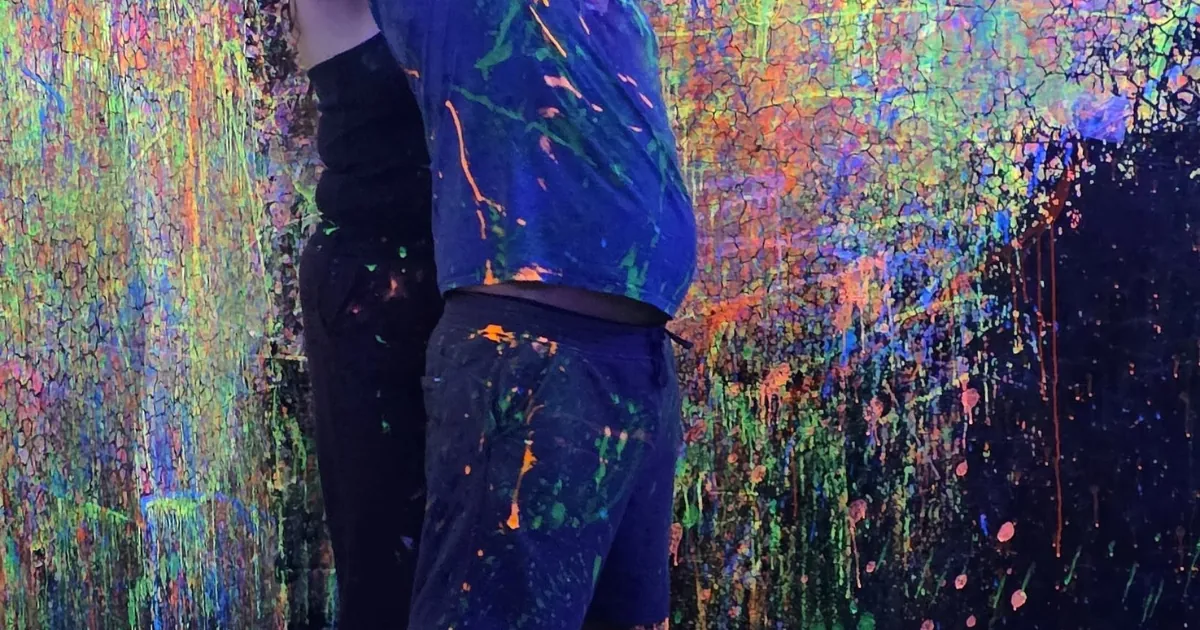 Paint-covered participant inside the Splatter Room at Smash & Splatter